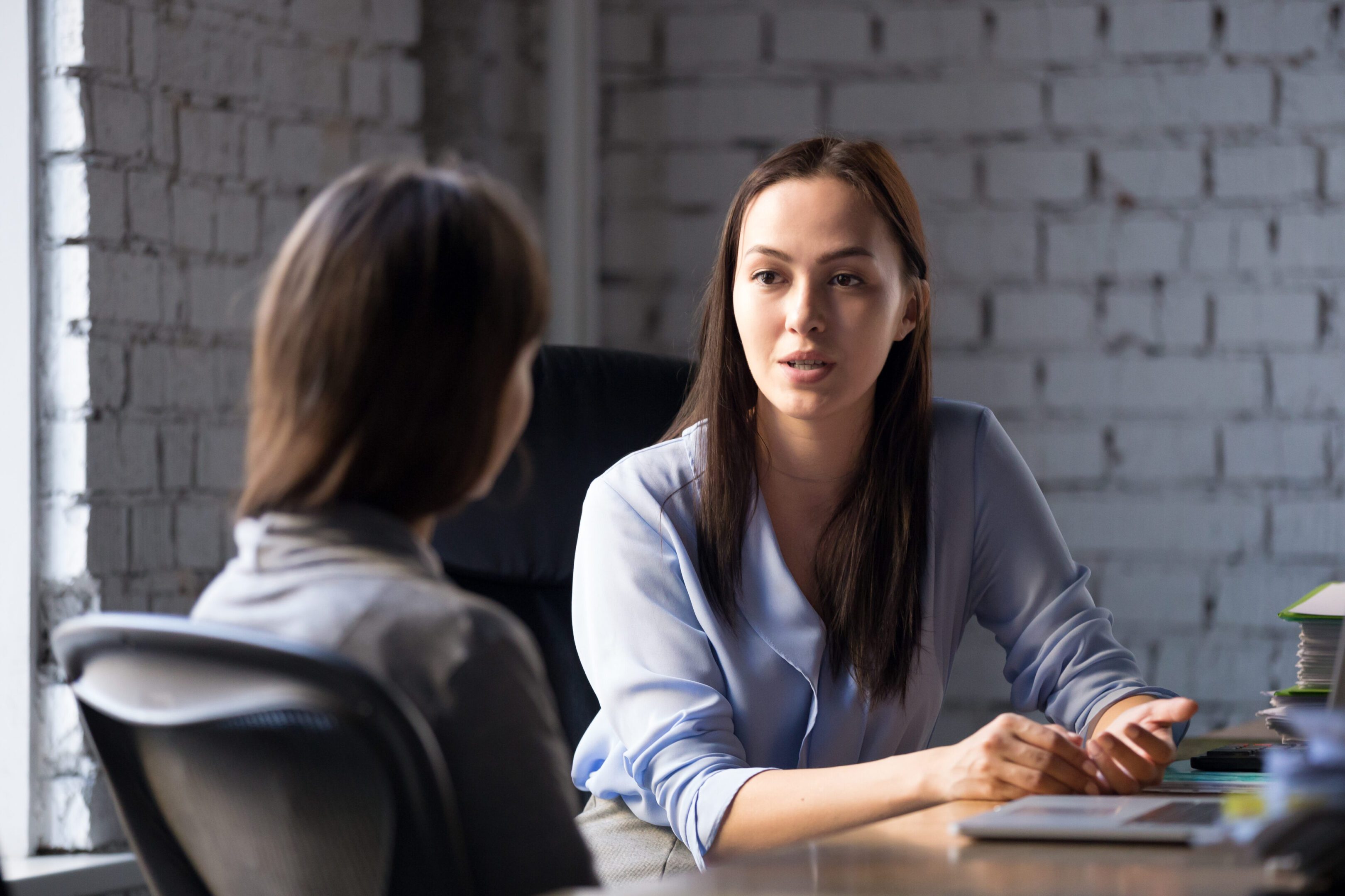 Serious professional female advisor consulting client at meeting Serious professional female advisor consulting client at meeting talking having business conversation or making offer, insurer giving advice, mentor teaching intern, hr speaking at job interview