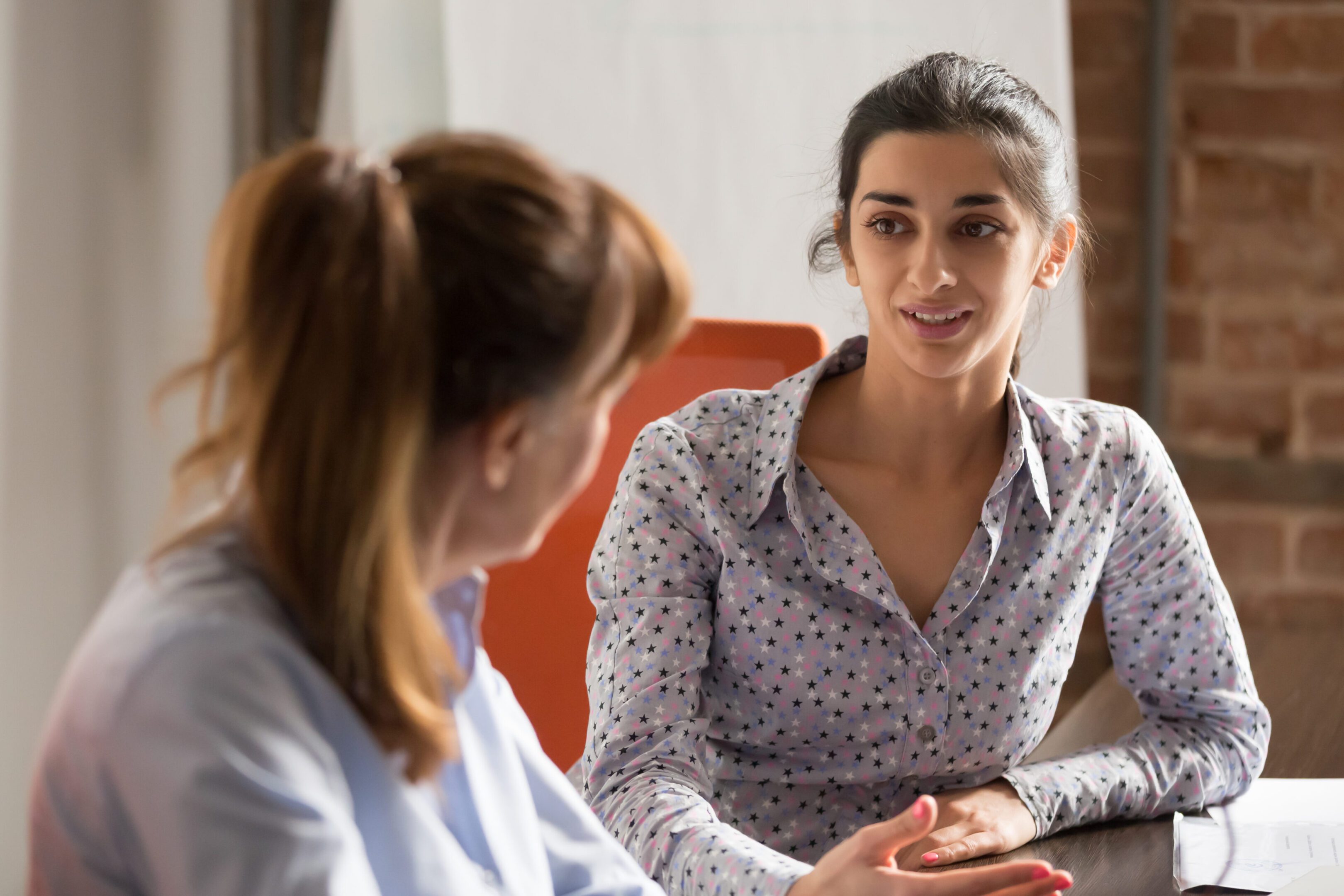 Indian businesswoman speaking consulting client at business office meeting Indian businesswoman speaking to colleague or hr during job interview, young professional hindu woman manager consulting client or explaining giving advice teaching at business office meeting