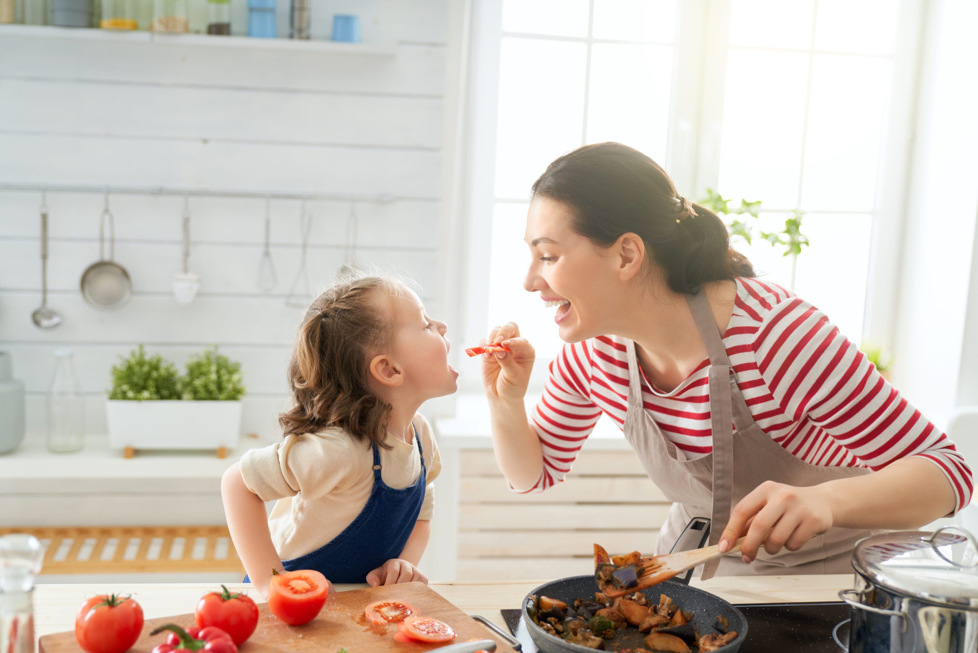 Happy family in the kitchen. Healthy food at home. Happy family in the kitchen. Mother and child daughter are preparing proper meal.