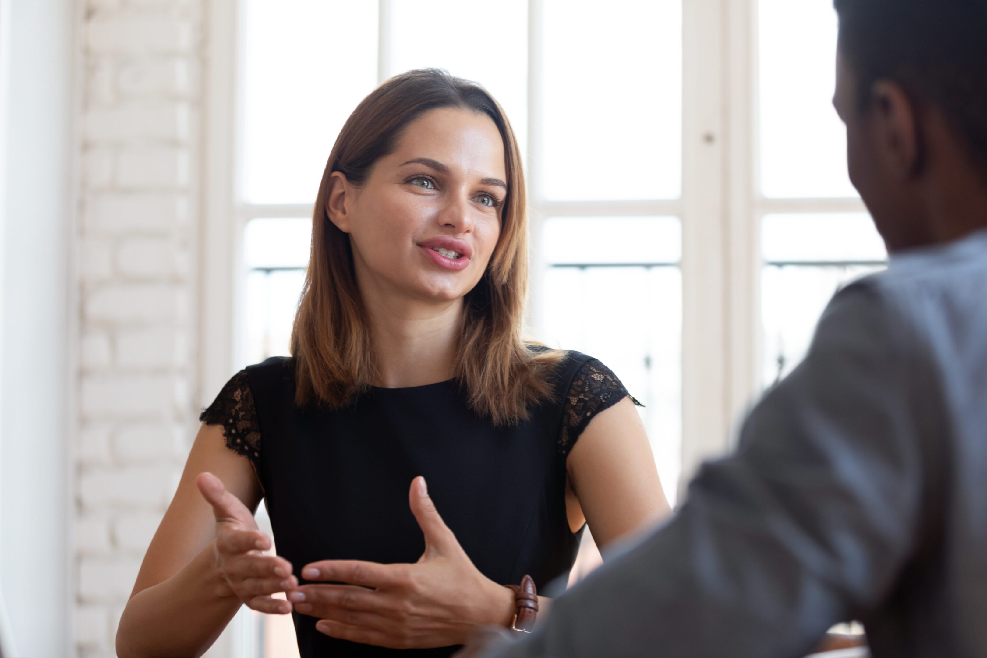 Happy pleasant young female financial advisor lawyer explaining contract details. Head shot focus on happy pleasant young female financial advisor Real Estate Agent lawyer explaining contract details to concentrated thoughtful african american male client at meeting in company office.
